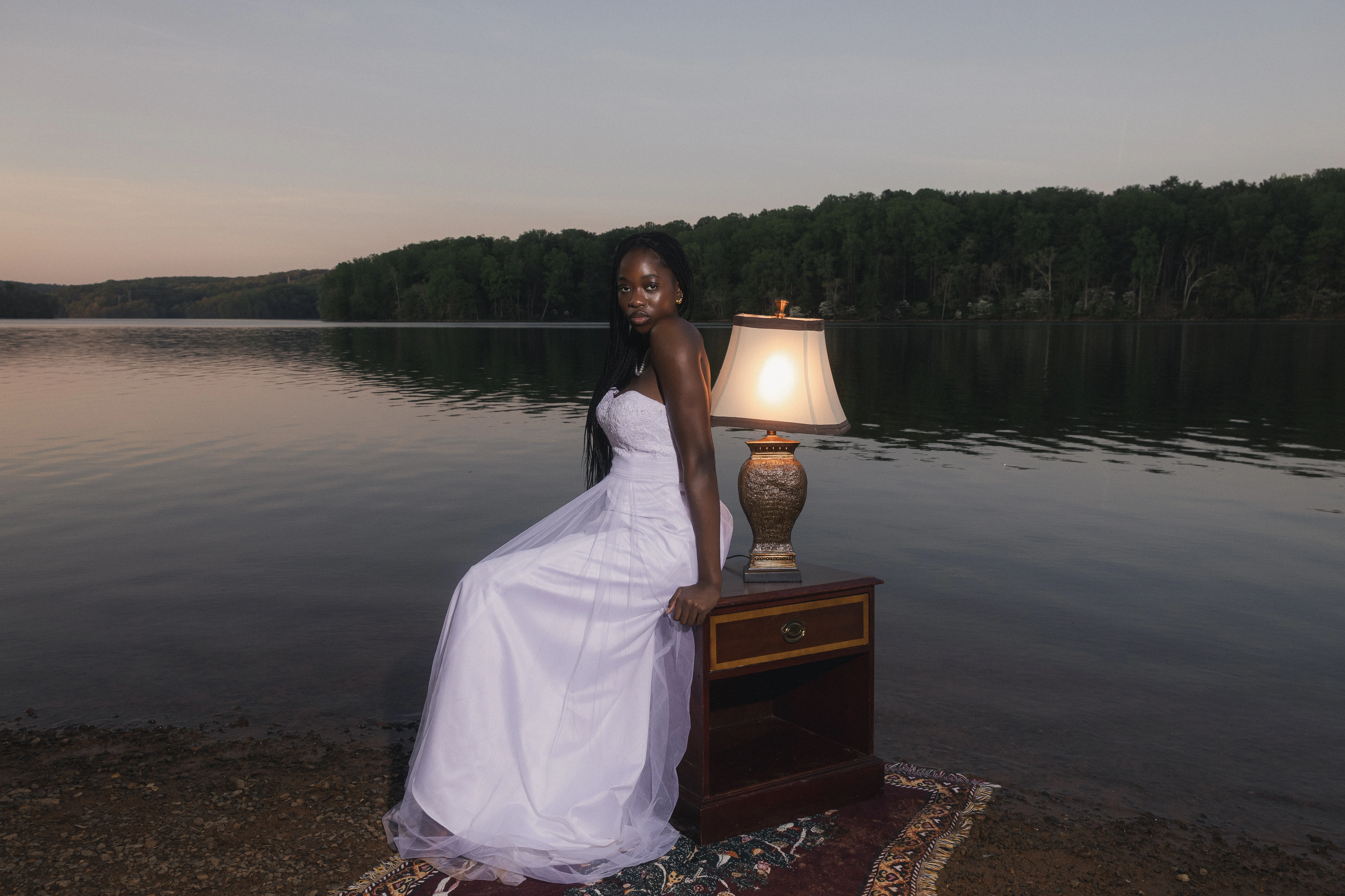 STILL editorial — model standing on a Persian rug as the gown flows in the wind by the lake